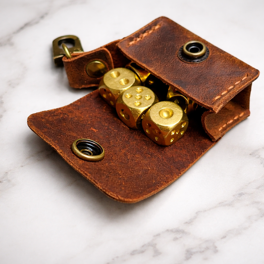 Brown leather dice pouch with gold dice on a marble surface