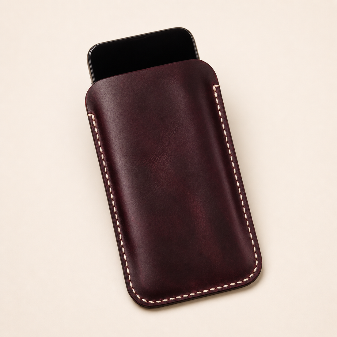 Handcrafted full-grain leather phone sleeve on a wooden desk