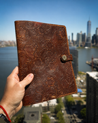 Hand holding a tooled floral leather Bible cover with New York City skyline in the background