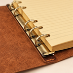 Detailed view of vintage leather six-ring notebook binder mechanism with ruled cream paper