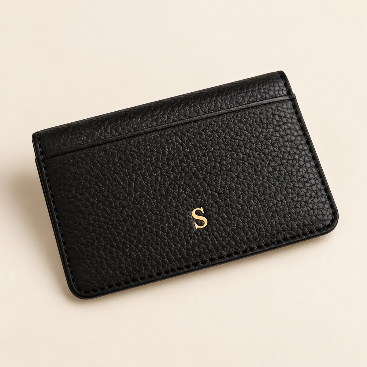 Black full-grain leather card holder personalized with a gold initial, premium studio photography