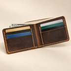 Open distressed brown leather bifold wallet with six card slots and US dollar bills