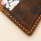 Macro detail of hand sewn stitching and distressed full grain leather texture on wallet