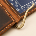 Close-up of metal money clip hardware and traditional leather hand stitching